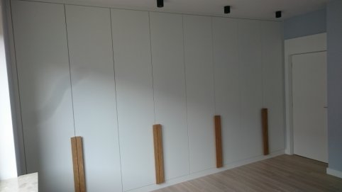 Nowoczesna duza zabudowa. szafa z drzwiami lakierowanymi otwieranymi z uchwytami z forniru